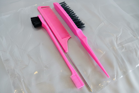 Three pink hairbrushes with black bristles on a reflective surface